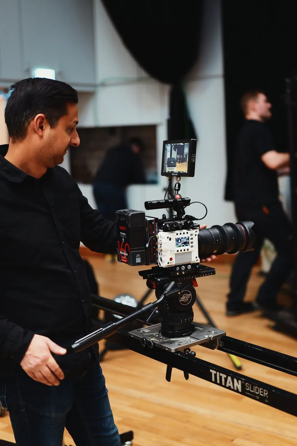 Mann bedient eine Filmkamera auf einem Slider im Studio.