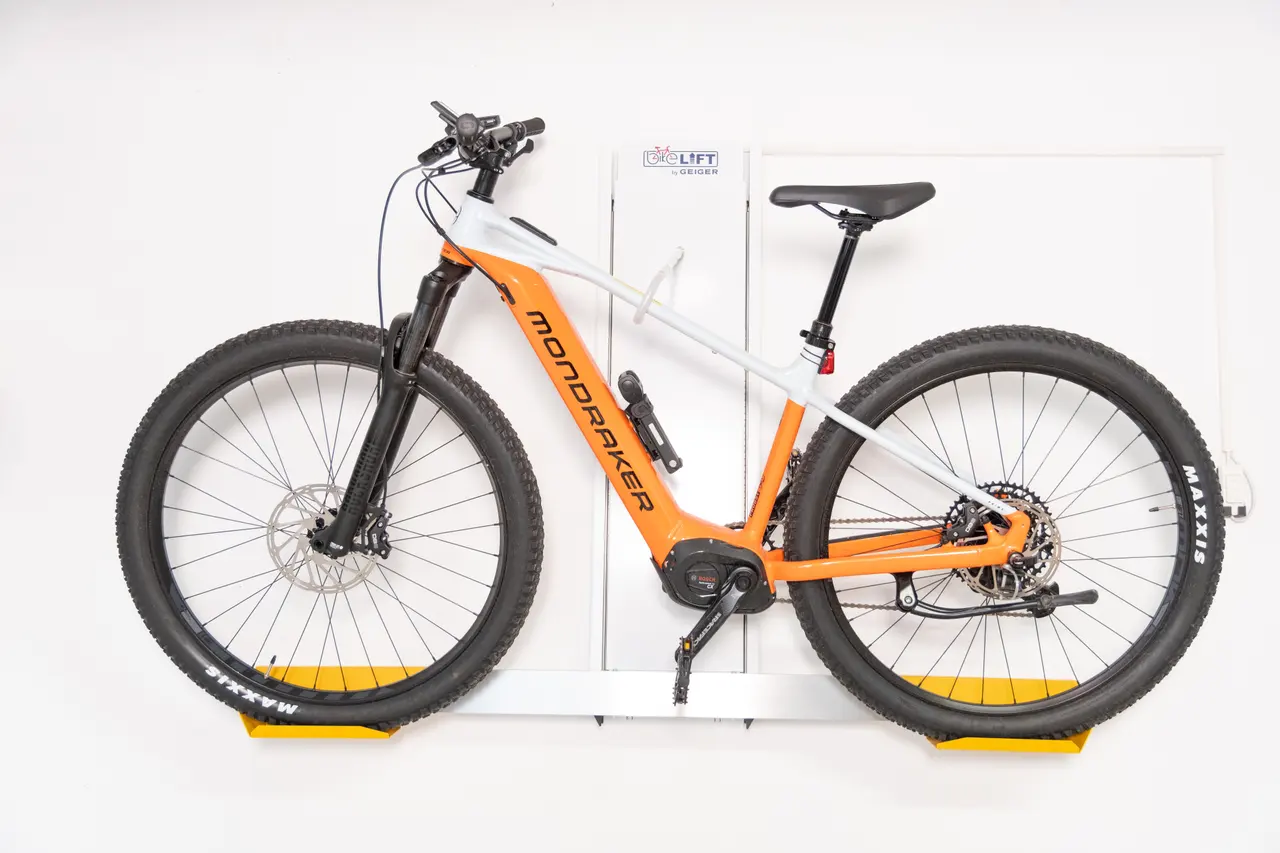 Orangefarbenes E-Bike im BIKELIFT an einer hellen Wand